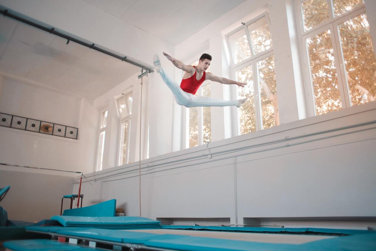 tornász performing straddle jump, egy kezdő torna mozog trambulin