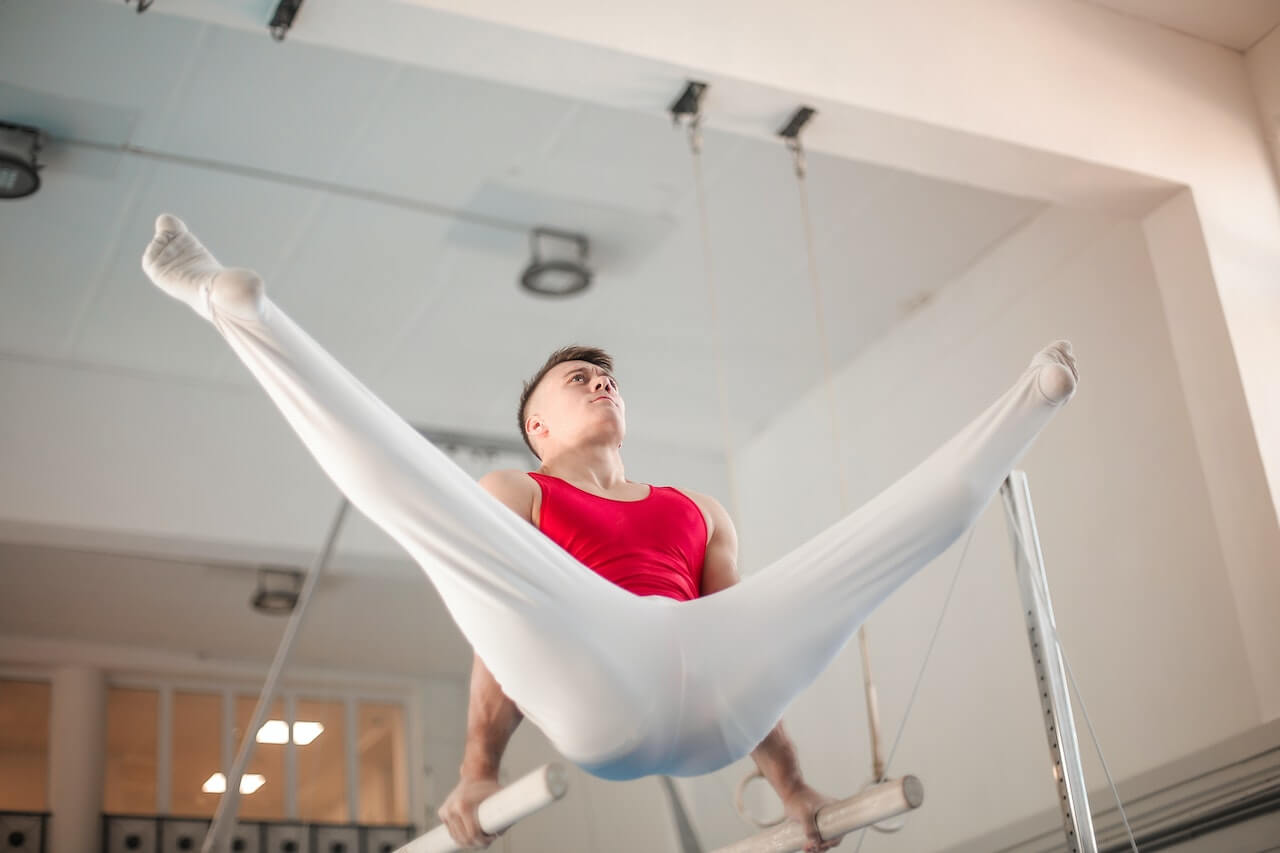 Man performing a straddle on parrallel bars. 