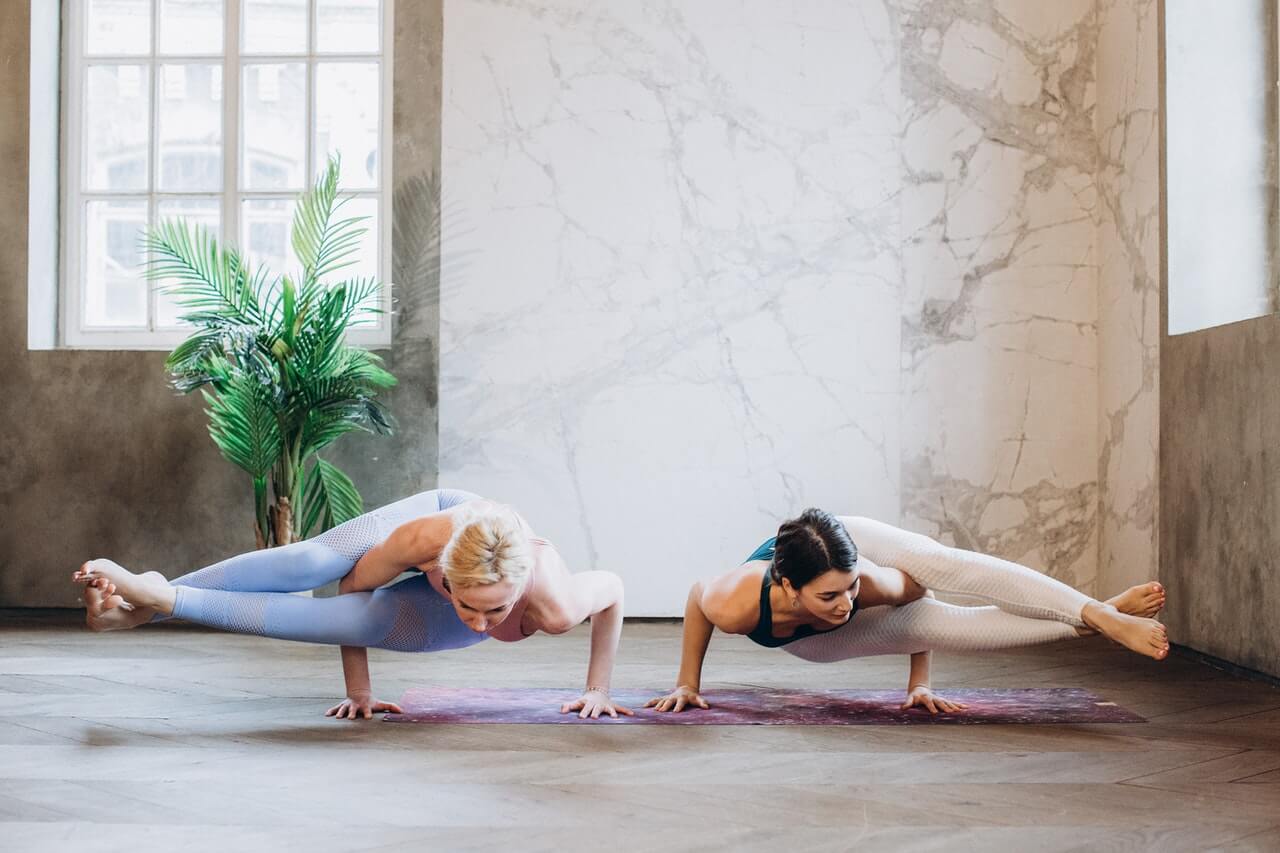 Two women practice yoga at a yoga studio