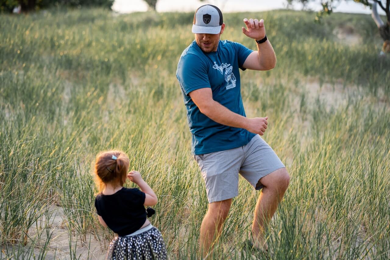 A father dances with his daughter outside