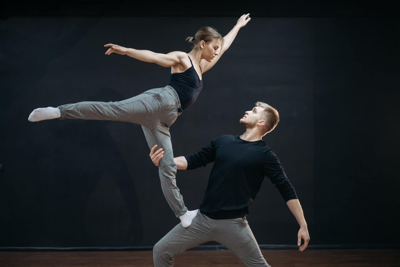 Dancer balancing on her partner's leg showing that balance is a benefit of dance