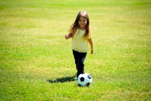 Girl playing soccer in an open green soccer field