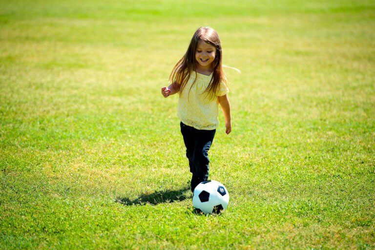 Girl playing soccer in an open green soccer field