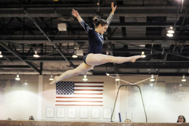 Woman in sport, competing in gymnastics on the balance beam.